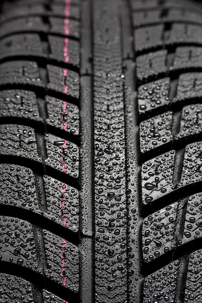 Neumáticos de coche closeup Estructura de perfil de rueda de invierno con gotas de agua sobre fondo negro azul