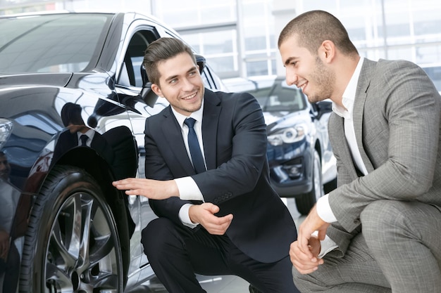 Esos neumáticos Concesionario profesional de automóviles en el salón de automóviles explicando los neumáticos del vehículo al cliente