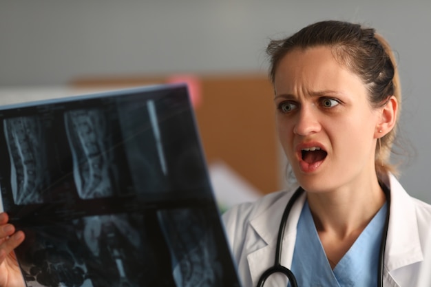 Neurologista da mulher segura um raio-x da coluna sacral na mão e fica surpresa