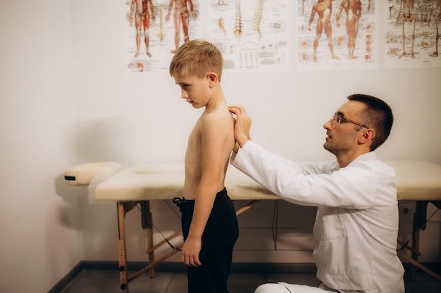 Un neurólogo pediátrico examina la espalda de una niña de 5 años que tiene dolor de espalda Tratamiento de dolor muscular y escoliosis en niños