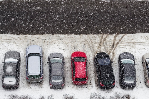 Nevando en la ciudad bajo la carretera con autos estacionados