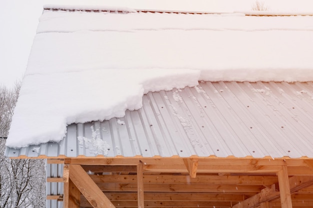 Neve deslizando para baixo do telhado casa de construção com telhado de metal coberto de neve gelada fresca e flocos de neve no dia de inverno gelado no subúrbio da vila temporada de inverno nevado clarão de clima frio