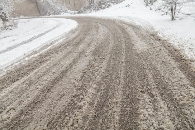 Foto neve solta na estrada na cidade condições de condução perigosas estrada gelada com trilhos de rodas de carro o conceito de condução segura em uma estrada escorregadia de inverno