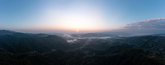 Névoa da montanha na silhueta do vale e vista aérea do fundo do céu azul da luz solar da manhã do drone no inverno Tailândia