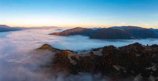 Névoa espessa entre picos de altas montanhas de outono ao nascer do sol