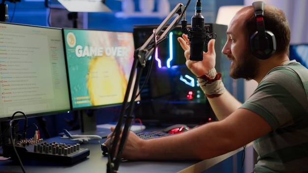 Nevous streamer perdiendo videojuego, juego terminado para hombre cyber jugando juegos de disparos espaciales en línea con auriculares. Jugador actuando en una potente computadora hablando con los jugadores en el chat en la competencia de juegos