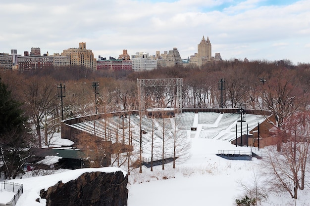 New York City Manhattan Central Park im Winter mit Schnee und Skyline der Stadt mit Wolkenkratzern, blauer bewölkter Himmel.