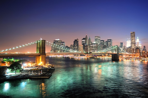 New York City Manhattan Downtown Skyline Luftaufnahme in der Abenddämmerung mit Wolkenkratzern über East River mit Reflexionen beleuchtet.