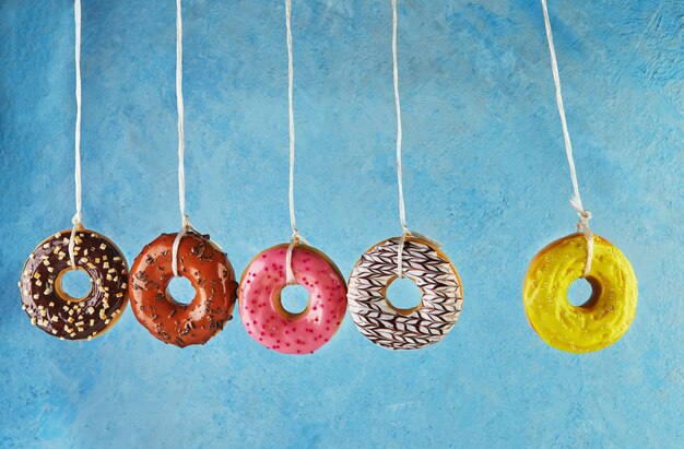 Foto newtons wiege mit bunten donuts mit zuckerguss und streuseln auf blauem grund.