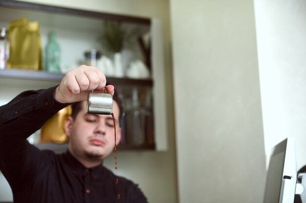 Ênfase nas gotas de café saindo do recipiente nas mãos de jovens baristas