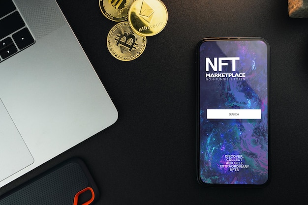 NFT NonFungible Token Marketplace na tela do smartphone na mesa preta com moedas criptográficas e ambiente de escritório do computador