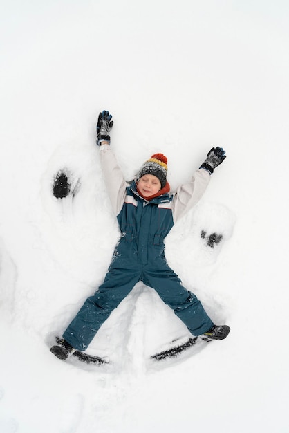 Ángel de nieve hecho por niño en la nieve. El niño yace en la nieve. Vacaciones de invierno. Vista superior.