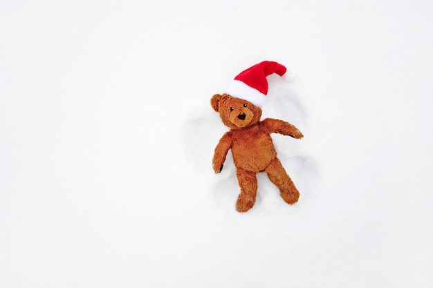 Ángel de la nieve, vista aérea - lindo oso de peluche en rojo gorro de Papá Noel divirtiéndose en las vacaciones de invierno