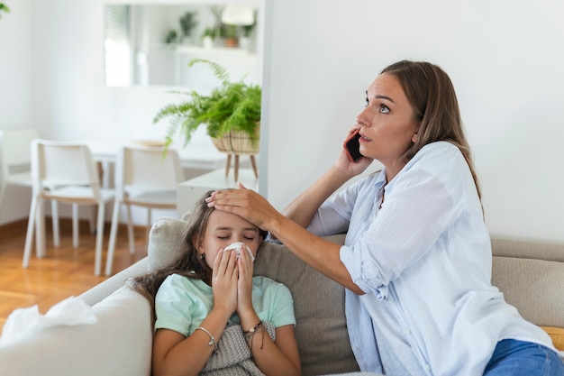 Ängstliche junge Mutter ruft Krankenwagenarzt an, kümmert sich um kranke kleine Mädchen mit Grippe und hoher Temperatur. Besorgte Mutter Kontakttherapeut oder Kinderarzt mit kleiner Tochter fühlen sich krank.