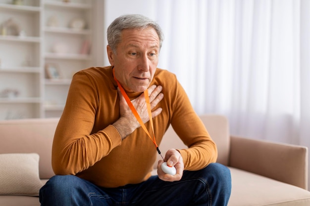 Ängstlicher kranker älterer Mann drückt auf den Panikknopf der Notfallgeräte
