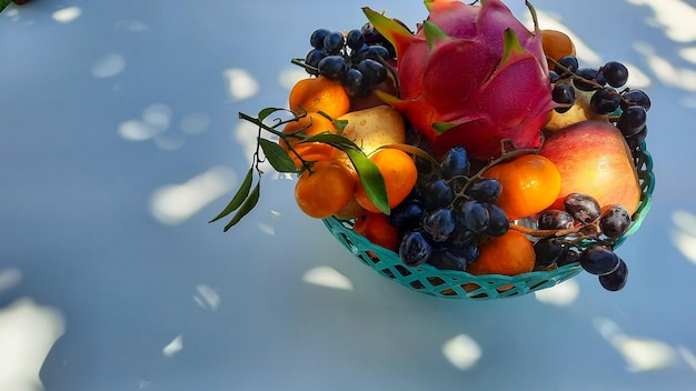 Ángulo alto, frutas del dragón tropical naranjas, peras, uvas en cesta verde sobre fondo blanco 01