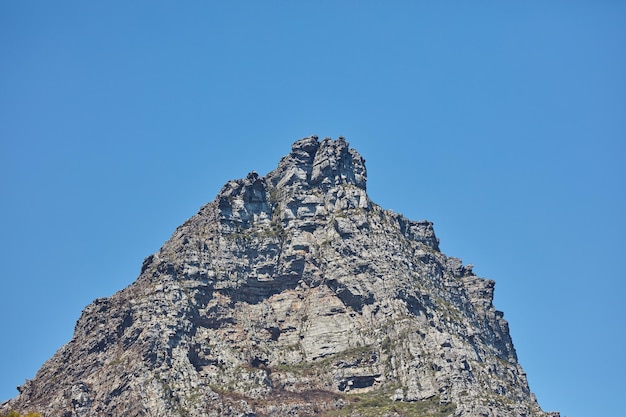 Ângulo baixo de um pico de montanha isolado contra um céu azul claro na África do Sul para o fundo do espaço de cópia Vista panorâmica e tranquila do topo da montanha e da paisagem rochosa de um local remoto em um dia ensolarado