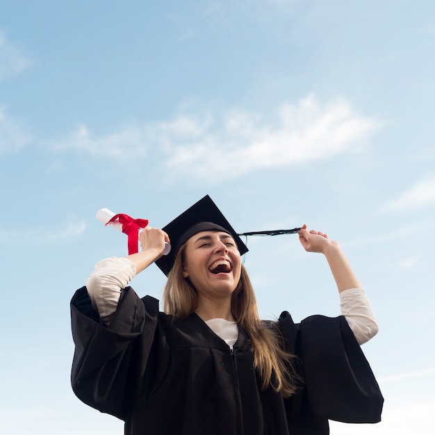 Ángulo bajo feliz joven celebrando su graduación