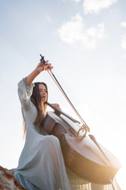 Ángulo bajo de mujer tocando el violonchelo con espacio de copia