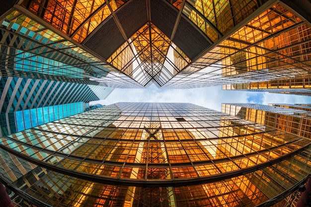 Ángulo no levantado del rascacielos de Hong Kong con reflejo de nubes entre edificios altos, vidrios de construcción, concepto comercial y financiero, arquitectura e industrial.