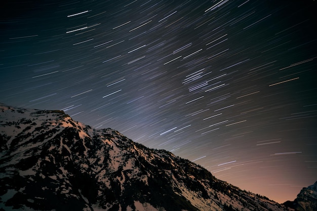 Ángulo bajo en el pico de una montaña nevada contra el impresionante cielo estrellado por la noche en el campo