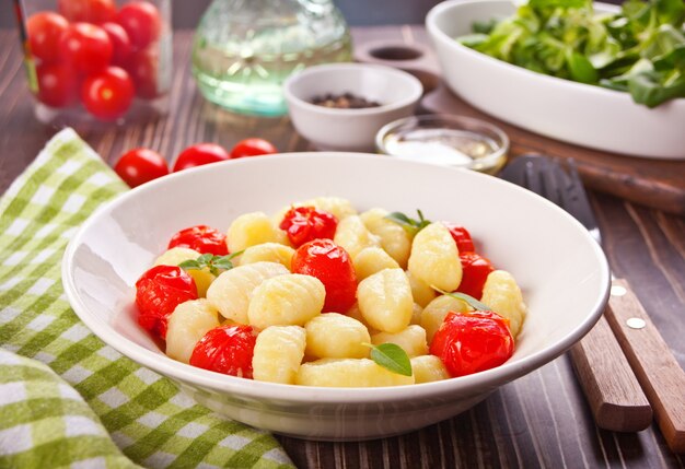 Nhoque caseiro italiano com tomate cereja na mesa de madeira