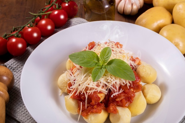 Foto nhoque com molho de tomate orgânico natural sem agrotóxicos com queijo parmesão ralado e folhas de manjericão.