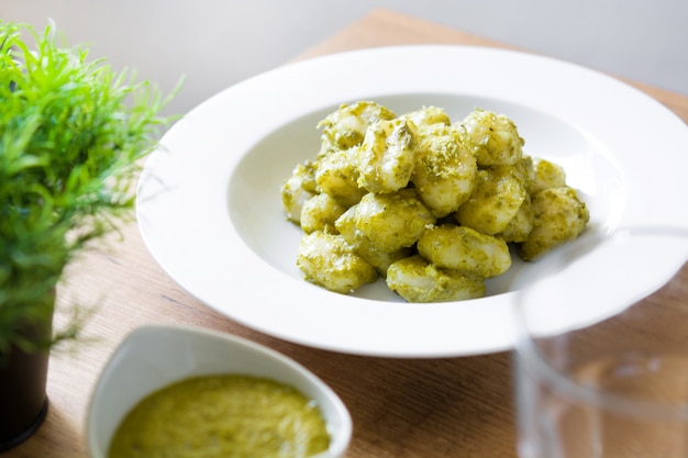 Nhoque com molho pesto no prato na mesa de madeira