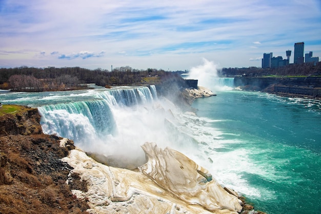 Niagara falls do lado americano e arranha-céus no canadá. uma vista sobre american falls, bridal veil falls, goat island, horseshoe falls e arranha-céus do canadá ao fundo.