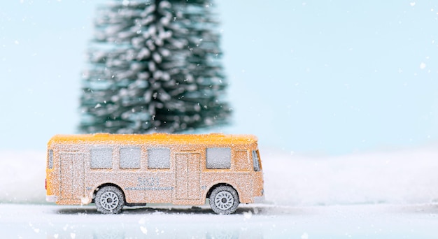 Ônibus amarelo em miniatura e pinheiro durante a queda de neve