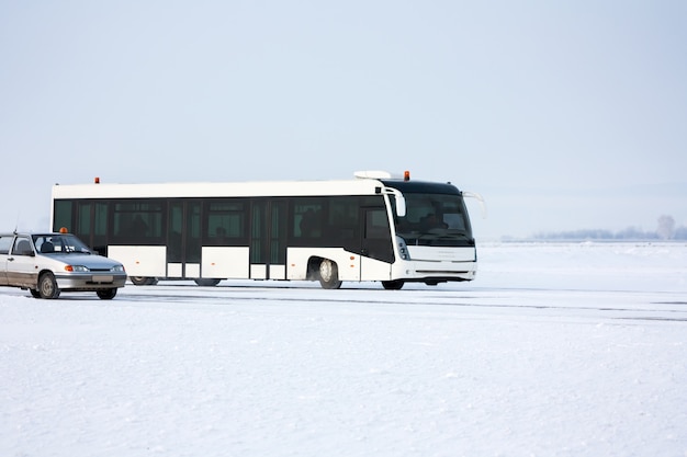 Ônibus do aeroporto e carro no avental de inverno