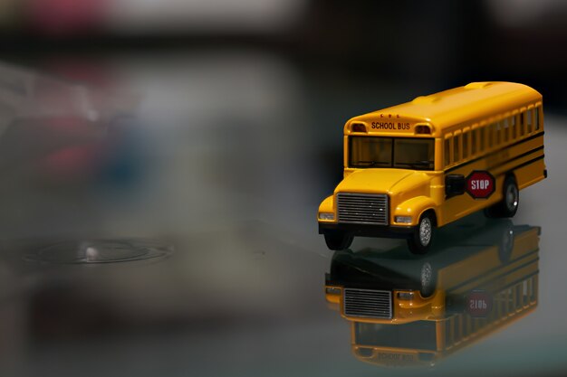 Ônibus escolar de brinquedo amarelo no vidro com reflexão