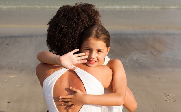 Foto nice menina e sua mãe ter um abraço na praia