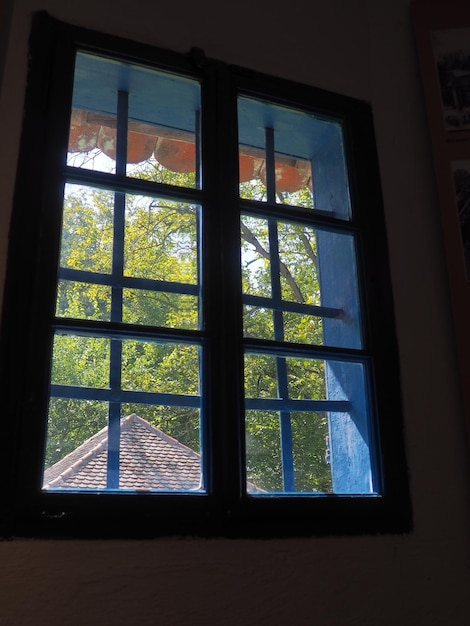Nicho de ventana en una casa antigua Parrilla de marco de ventana y vidrio viejo Fuera de la ventana es un día de verano Arquitectura rural tradicional eslava Trsic Loznica Serbia
