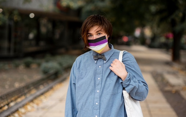 Foto nicht binäre person, die eine medizinische maske mit repräsentativer flagge trägt