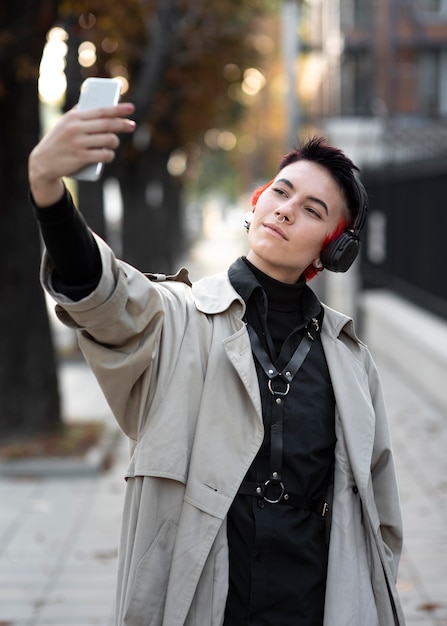 Nicht binäre Person mit moderner Frisur, die ein Selfie im Freien nimmt