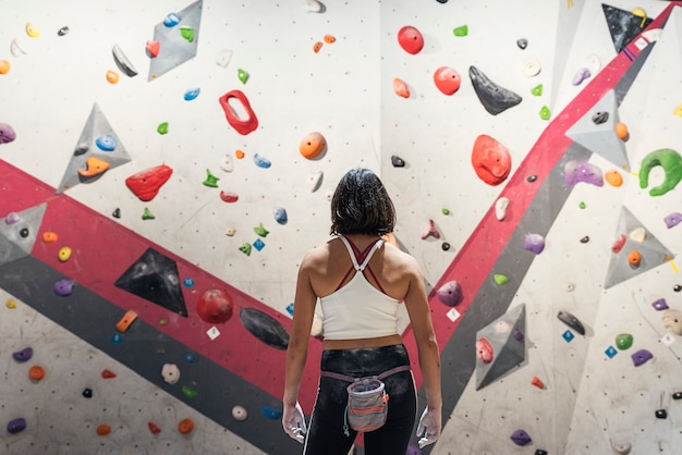 Nicht erkennbare Frau, die bereit ist, Klettern auf künstlicher Wand im Innenbereich zu üben. Aktiver Lebensstil und Boulderkonzept.