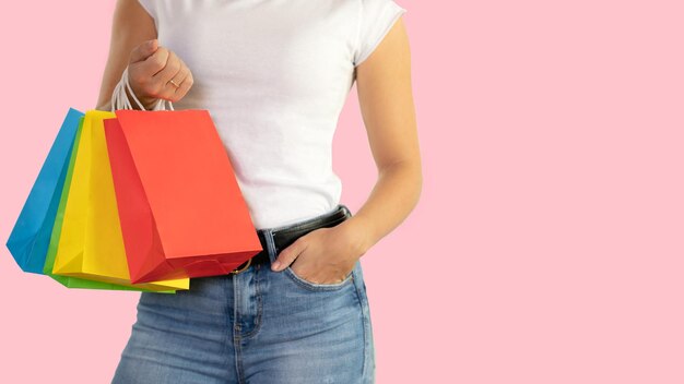 Nicht erkennbare frau, die bunte taschen auf einem rosa hintergrund mit kopienraum hält einkaufskonzept verkäufe schwarzer freitag weihnachten