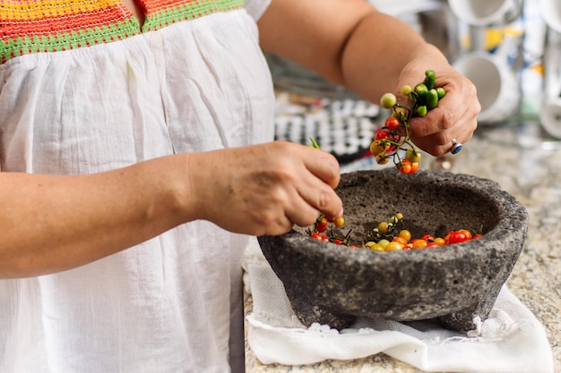 Nicht erkennbare Frau, die eine traditionelle mexikanische Sauce in einem Molcajete macht