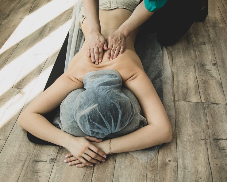 Foto nicht erkennbare frau, die shiatsu-massage durch fachmann auf holzboden im salon hat