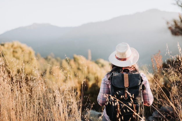 Nicht erkennbare Frau mit Hut und Rucksack beim Trekking durch das Feld