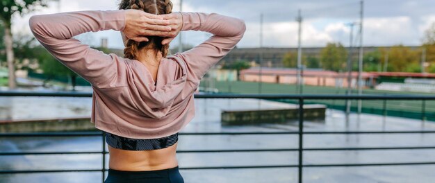 Nicht erkennbare junge Sportlerin, die sich im Freien Hals und Schultern streckt