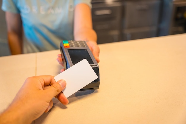 Nicht erkennbare Kellnerin, die das Datentelefon zum Sammeln mit dem Kontakt mit der Kreditkarte des Kunden überreicht