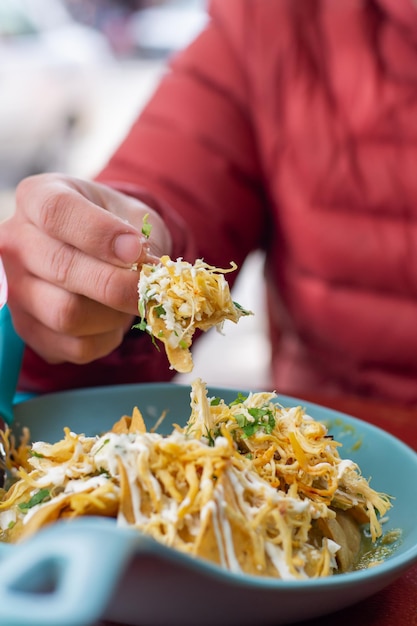 Foto nicht erkennbare person, die traditionelle mexikanische chilaquiles isst