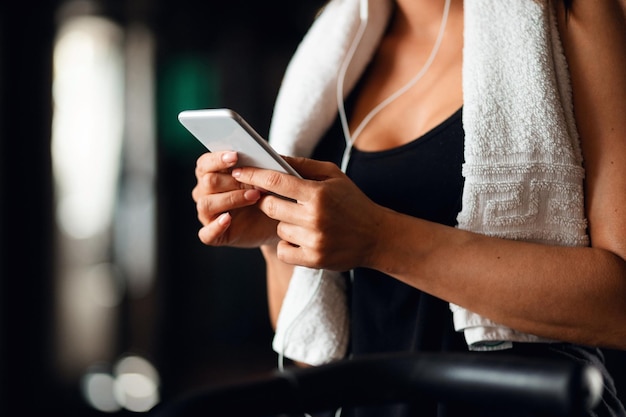 Nicht erkennbare Sportlerin SMS auf Smartphone beim Training in einem Fitnessstudio