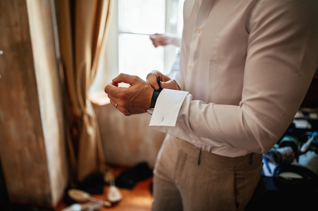 Nicht erkennbarer Bräutigam, der eine Armbanduhr zur Hand legt, während er sich für seinen Hochzeitstag anzieht