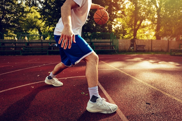 Nicht erkennbarer junger Straßenbasketballspieler, der seine Fähigkeiten auf dem Platz zeigt.