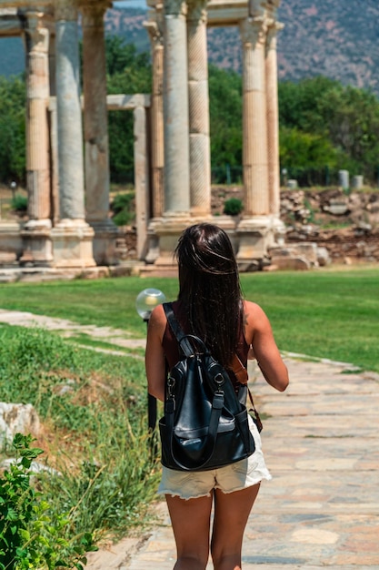 Nicht erkennbarer junger Tourist, der im Vordergrund mit dem Tempel der Aphrodisia im Hintergrund in der Türkei spaziert