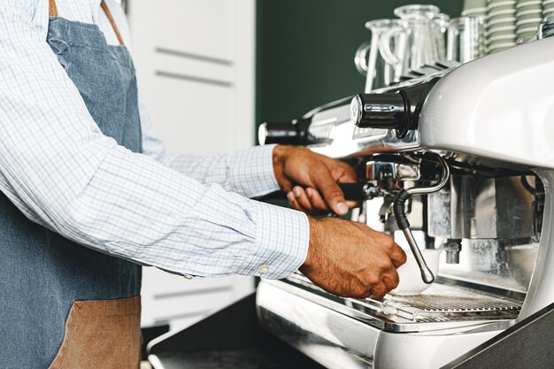 Nicht erkennbarer mann barista, der kaffee auf professioneller kaffeemaschine zubereitet