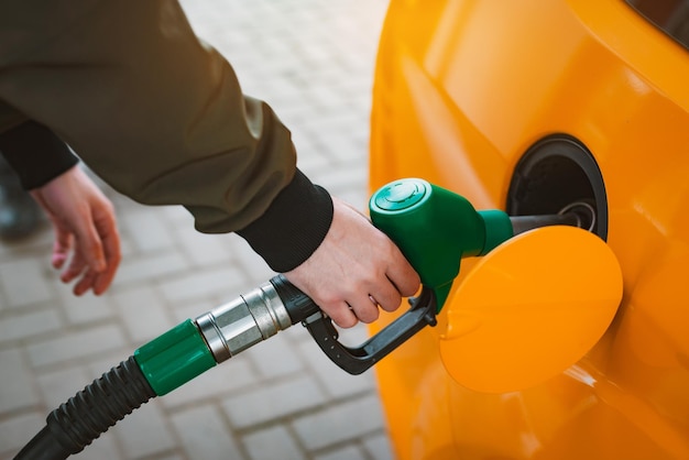 Nicht erkennbarer Mann, der Auto von der Tankstelle betankt, die Benzinkraftstoff im Auto an der Tankstelle füllt Konzept für hohe Benzinpreise